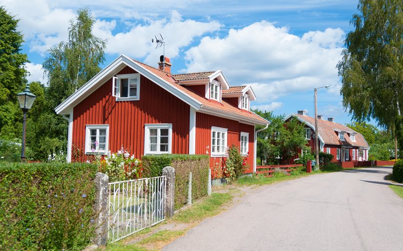 Idyllisches Dörfchen in Schweden. Rote Schwedenhäuser stehen an einer Straße. Sonniges Wetter