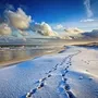 schneebedeckter Nordseestrand mit Fußspuren